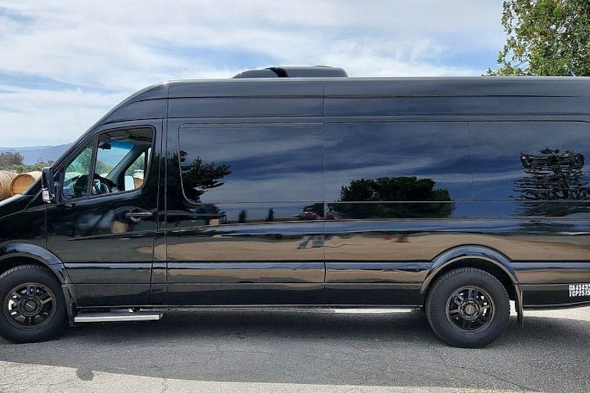 A black van parked on a road with a clear sky. 2