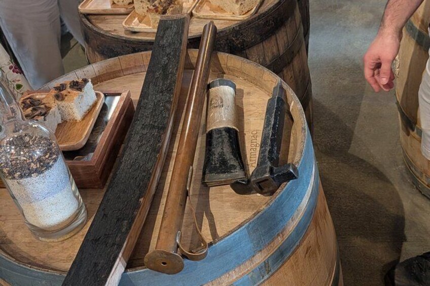 A wooden barrel with tools, a long metal rod, and a glass container with a white substance. 4