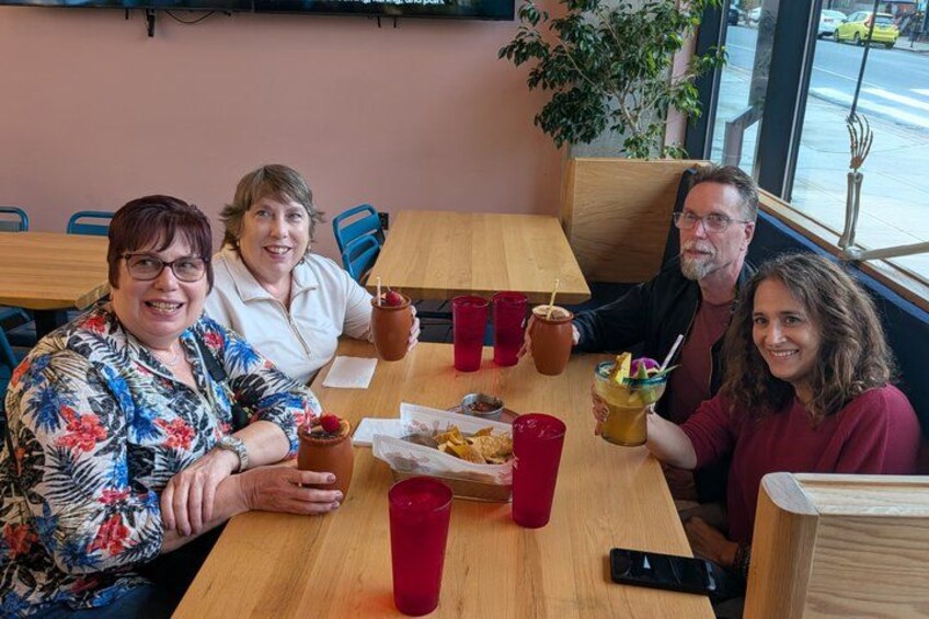A group of people sitting at a wooden table in a cafe with red cups and a phone on the table. 2