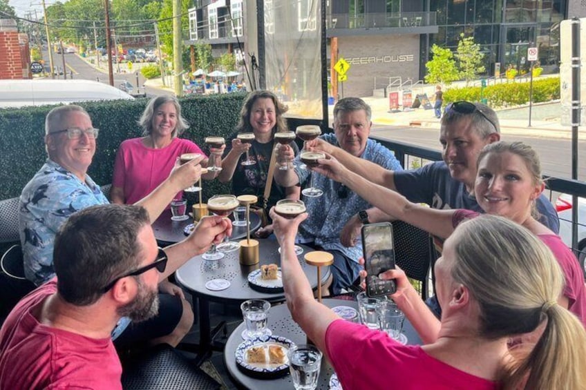 A group of people toasting at a table outdoors with a building in the background. 2