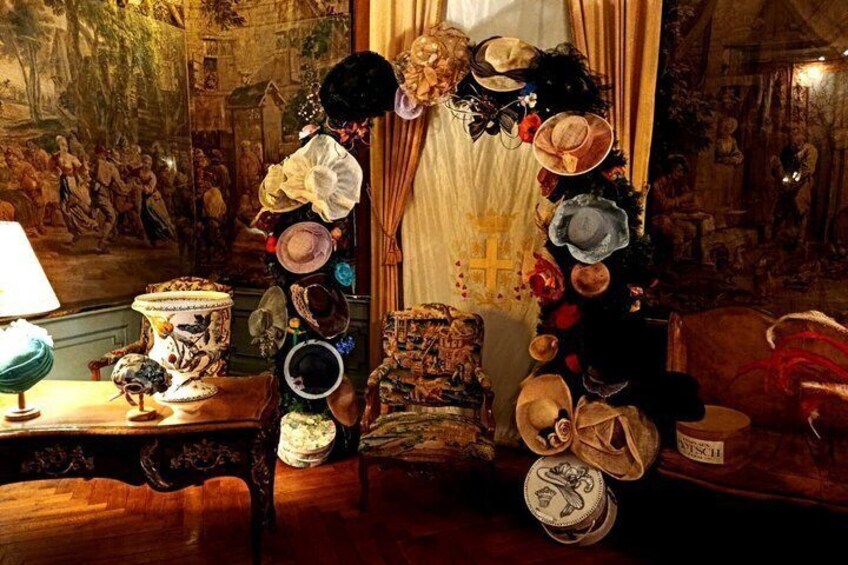 Una stanza con una collezione di cappelli appesi a una parete, un tavolo con una lampada e un quadro sulla parete. 1