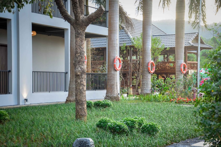 A modern building with a white facade, surrounded by lush greenery and palm trees. 2
