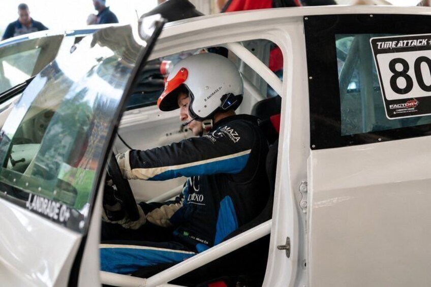 A person in a racing suit inside a vehicle with a 'TIME ATTACK' sign and the number '80' on the window. 1