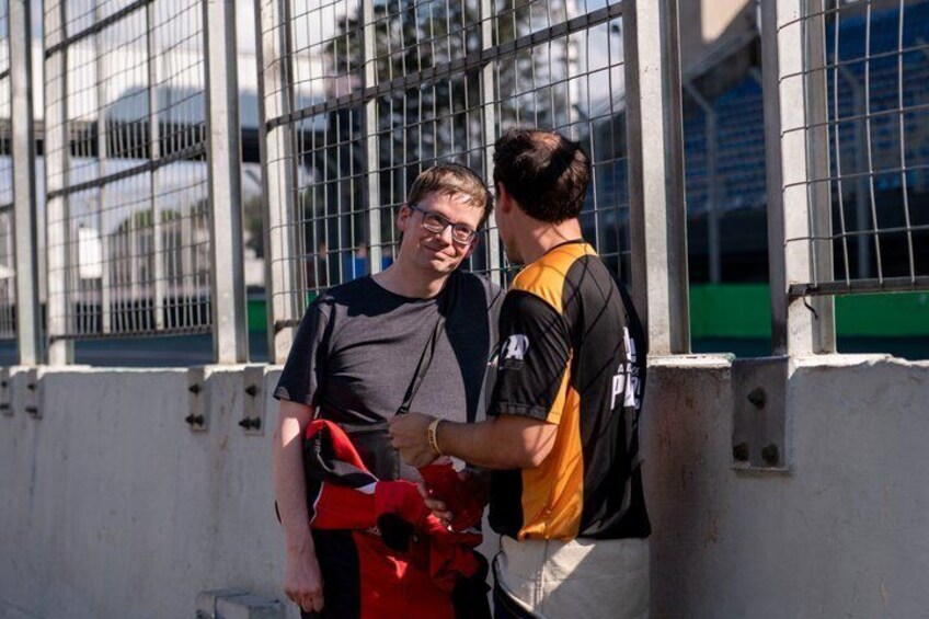 Two people shaking hands near a metal fence with a building in the background. 2