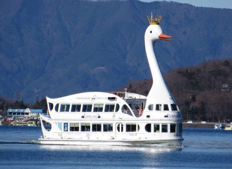A swan-shaped boat named 'Yamanakako Swan Lake' with a golden crown on its head, floating on water with mountains in the background. 5