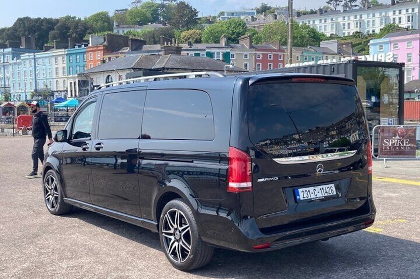 Ein schwarzer Mercedes-Benz-Transporter steht auf einer Straße, im Hintergrund sind Gebäude zu sehen. 1