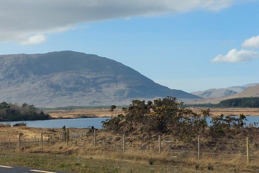 Un paysage montagneux avec un lac et une zone délimitée par une clôture, où la végétation est clairsemée. 3