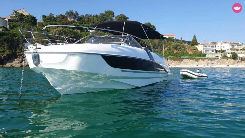 A white yacht anchored near a beach with houses in the background. 1