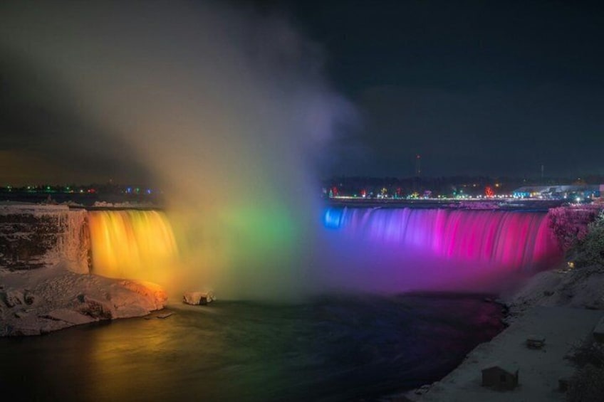 A waterfall with a rainbow effect, a river, and a cityscape in the background. 5
