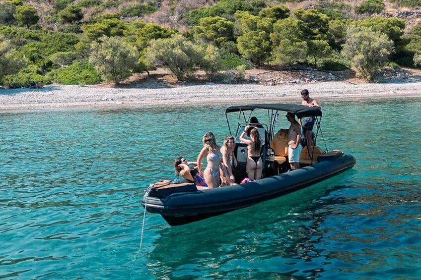 En båt med människor ombord på ett klart, blått hav, omgiven av en klippig kust med gles vegetation. 5