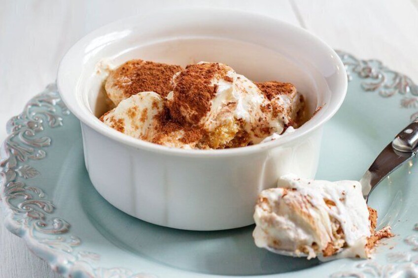 A bowl of dessert with whipped cream and a sprinkle of cocoa on a blue plate. 5