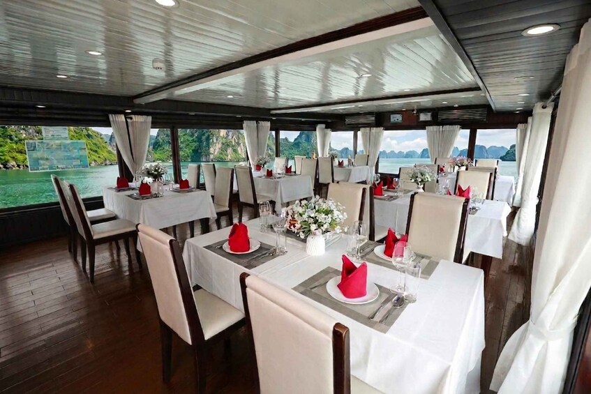 A dining area with tables set for a meal, overlooking a body of water with greenery and mountains in the distance. 5