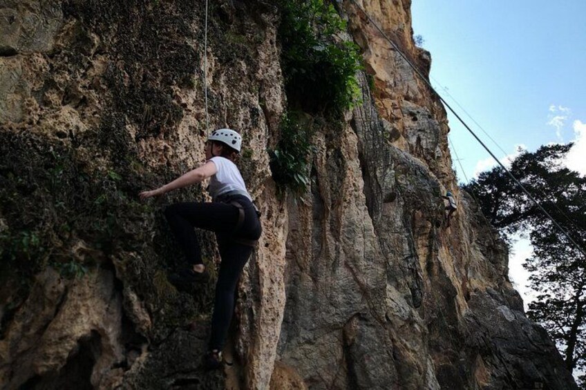 A person climbing a rocky cliff with a helmet and harness. 5