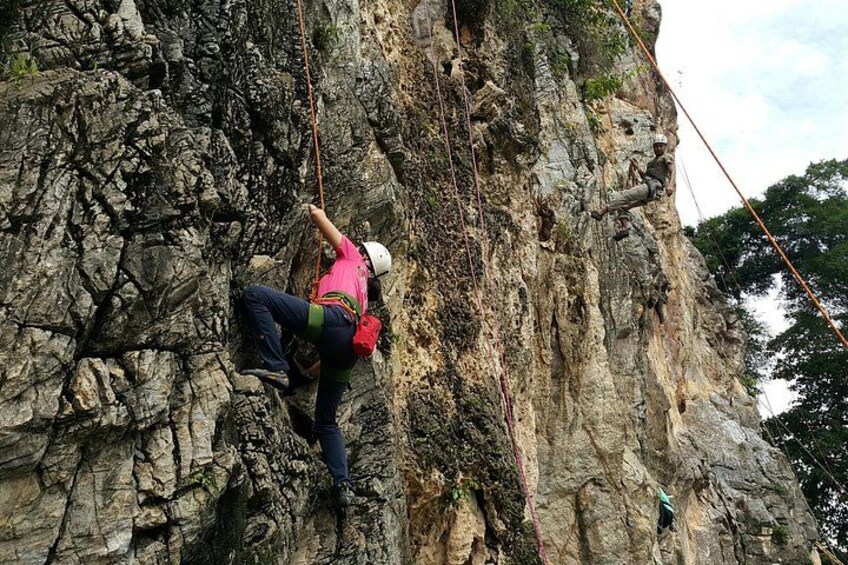 A person climbing a rocky cliff with ropes. 3