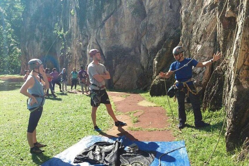 A group of people engaged in rock climbing, with a rocky cliff and a path in the foreground. 4