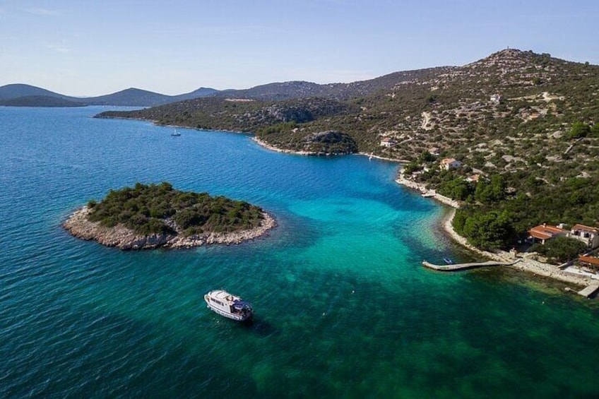 Eine Küstenlandschaft mit einer kleinen Insel, klarem türkisblauem Wasser und einem Boot. 5