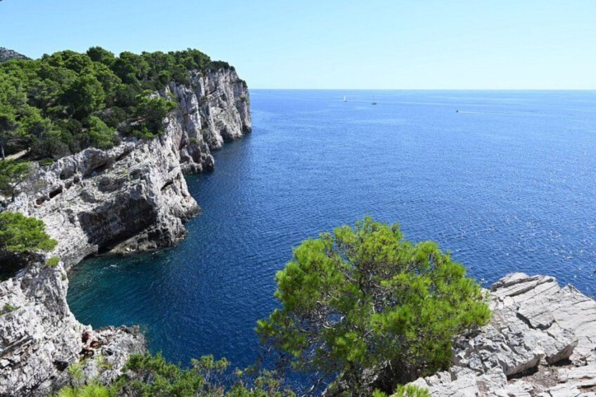 A coastal landscape with rocky cliffs, clear blue sea, and green vegetation. 5