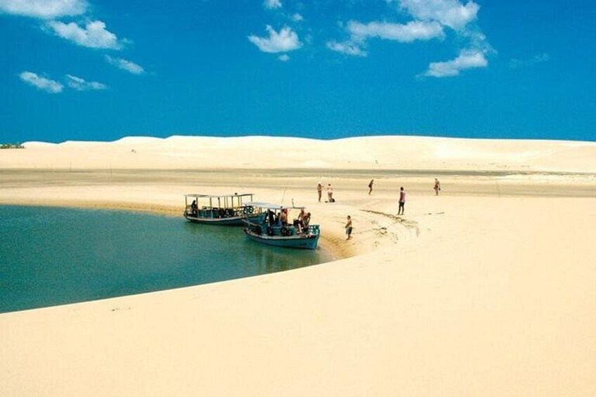 Una barca su un'acqua calma, circondata da dune di sabbia. 2