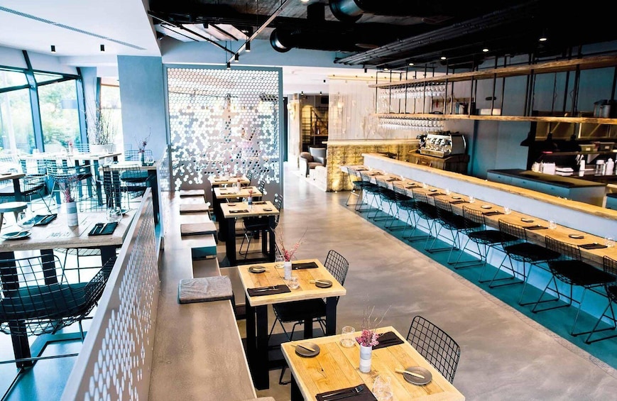 A modern restaurant with high tables and chairs, a bar area, and a decorative wall with hexagonal patterns. 1