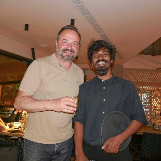 Two people standing indoors, one holding a drink and the other holding a plate. 5