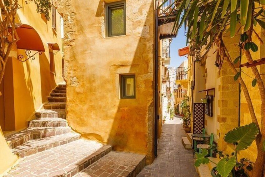 A narrow street with steps leading up to a building, surrounded by yellow walls and greenery. 2