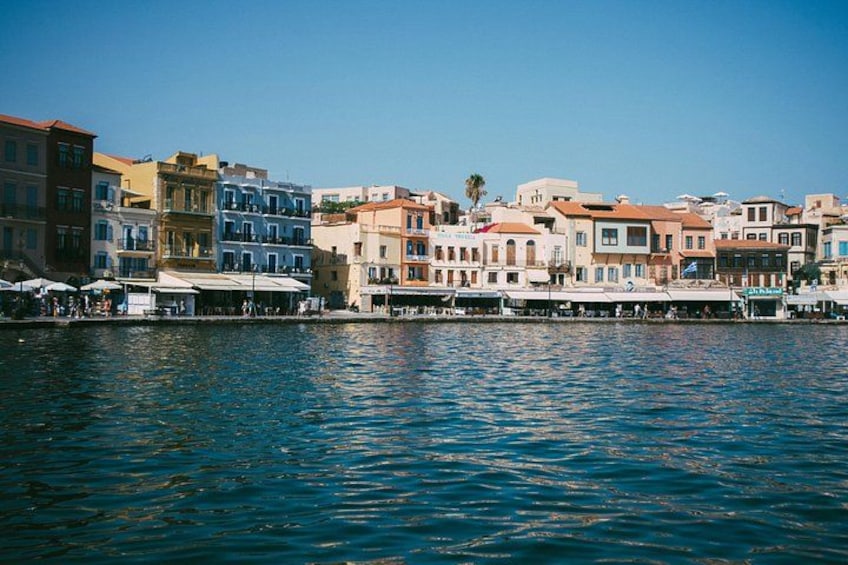 A waterfront with colorful buildings, a calm sea, and a clear sky. 5