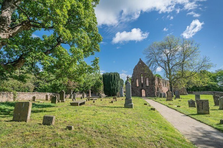 A cemetery with gravestones, a stone church, and a large tree. 4