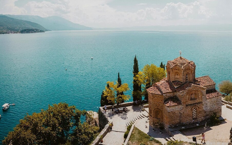 A church by a lake with mountains in the background. 5