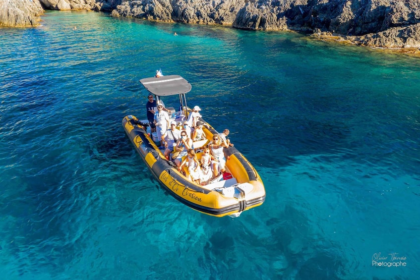 A yellow inflatable boat with people on a clear blue sea. 2