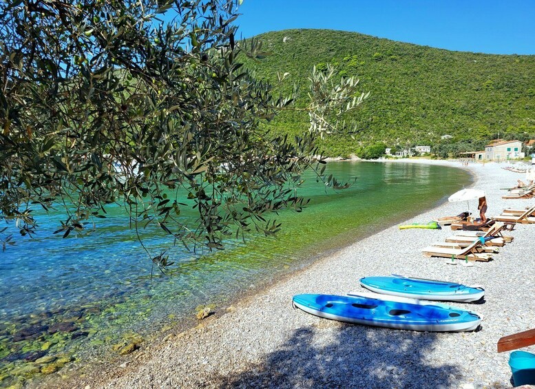 A clear turquoise sea, a pebble beach, and a row of blue kayaks. 3