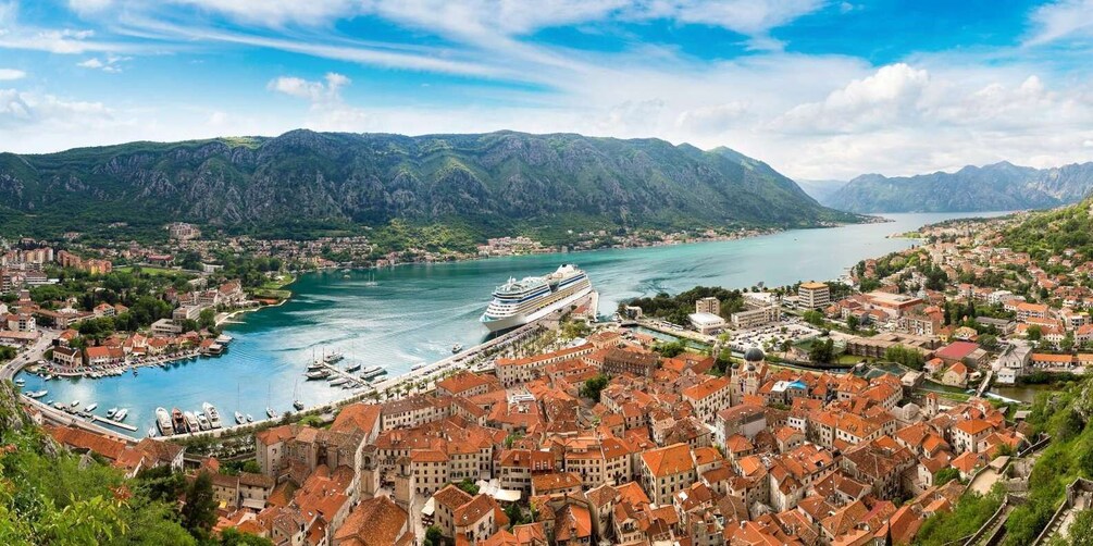 A coastal town with a cruise ship docked, surrounded by mountains and a harbor. 2