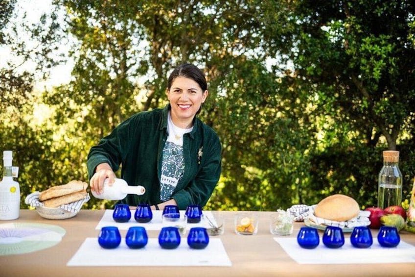 A person pouring a liquid into blue glass vases on a table outdoors. 1