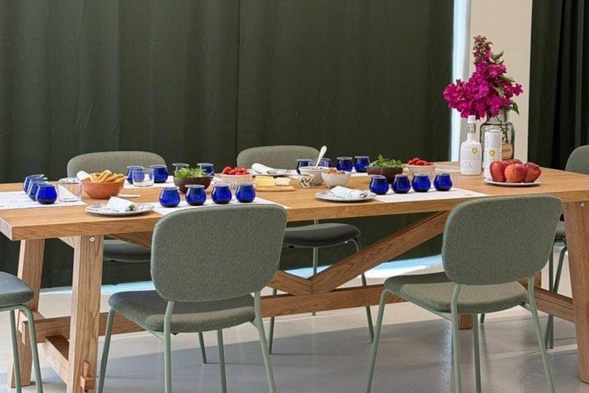 A dining table set with blue cups, bowls, and plates, surrounded by chairs. 5