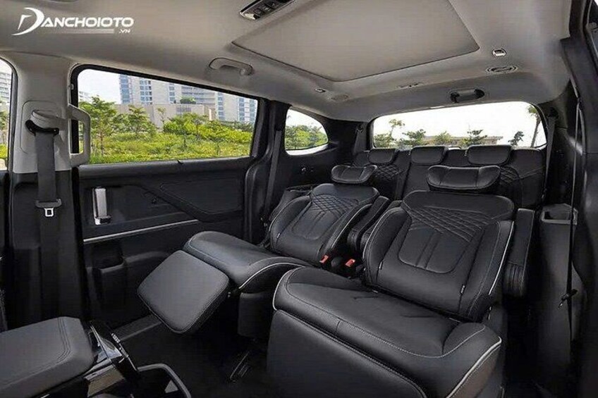 A vehicle interior with black leather seats, a sunroof, and a visible cityscape through the windows. 2