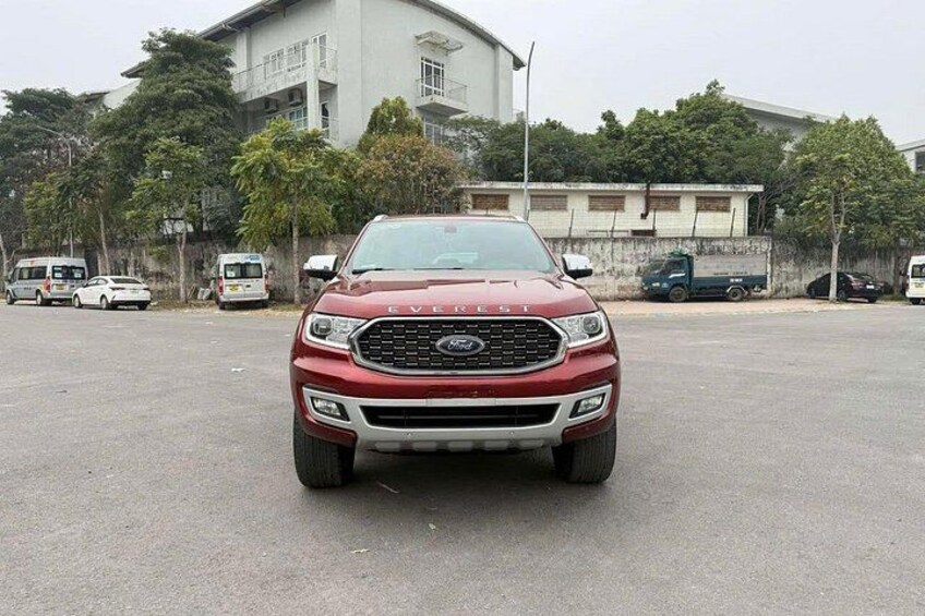 A red Ford SUV parked in a lot with buildings and trees in the background. 5