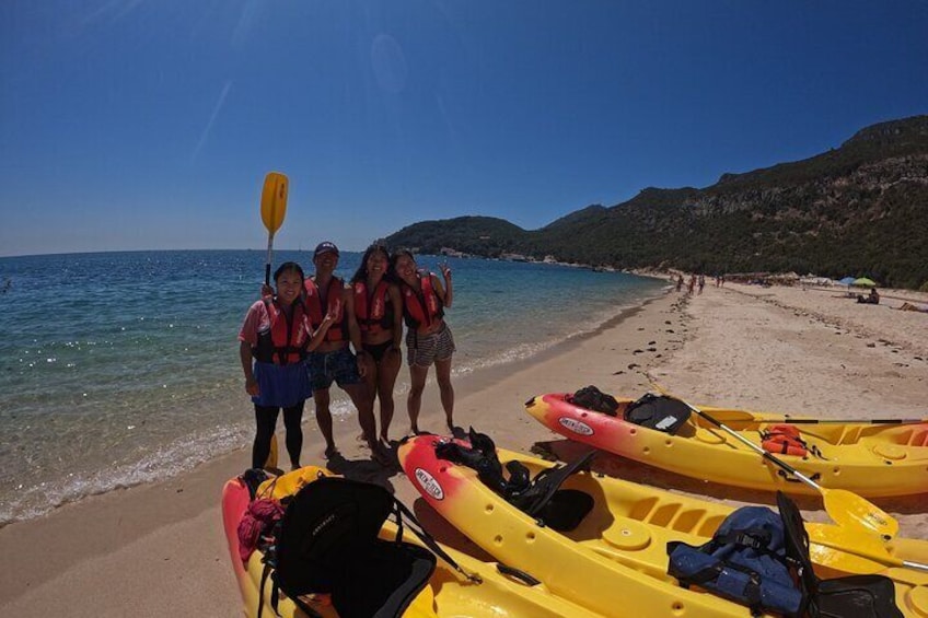 A group of people on a beach with kayaks and a paddle. 2