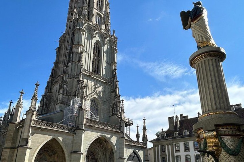 A Gothic cathedral with a tall spire, a statue on a column, and a clear blue sky. 2
