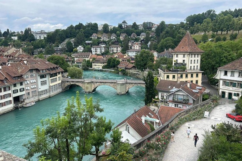 A river with a bridge, buildings, and a pedestrian path. 5