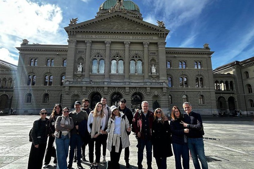 A group of people standing in front of a large, historic building with arched windows and a dome. 3