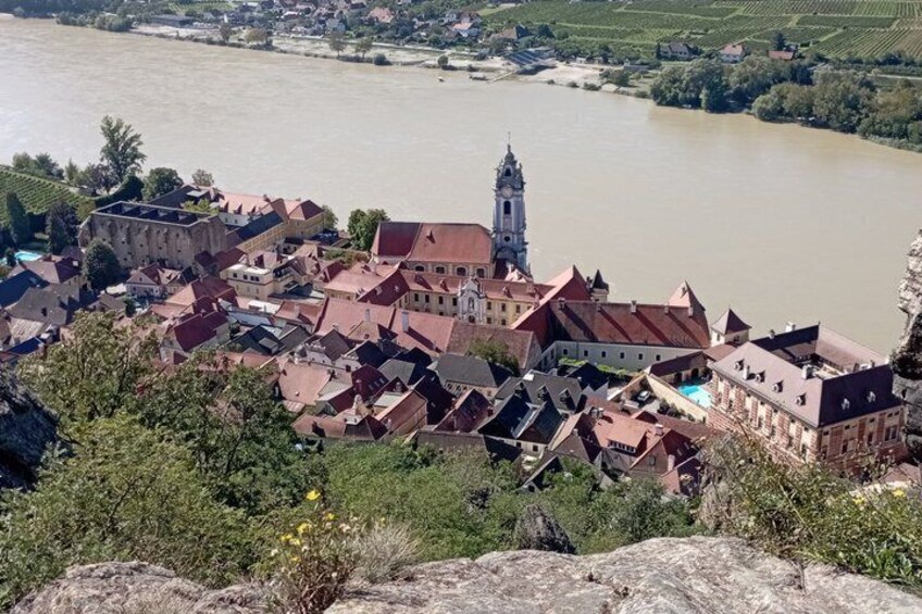 A town with a prominent tower, river, and surrounding greenery. 2