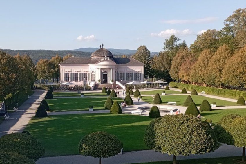 A classical building with a dome, surrounded by manicured gardens and trees. 3
