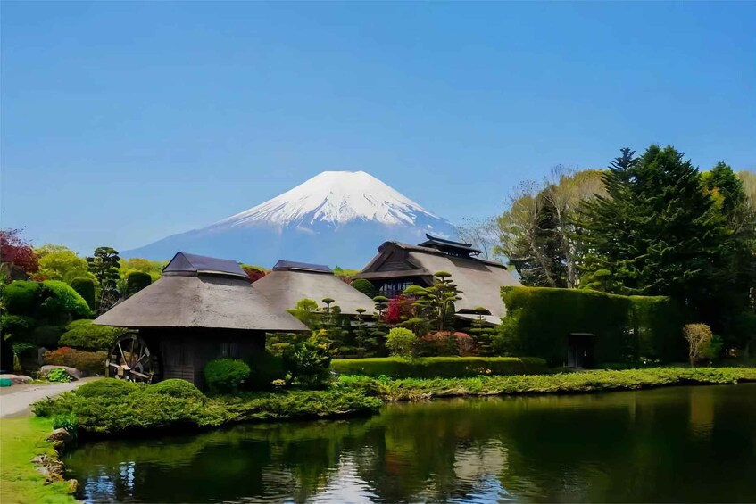 A traditional Japanese garden with a pond, thatched-roof buildings, and a backdrop of Mount Fuji. 2