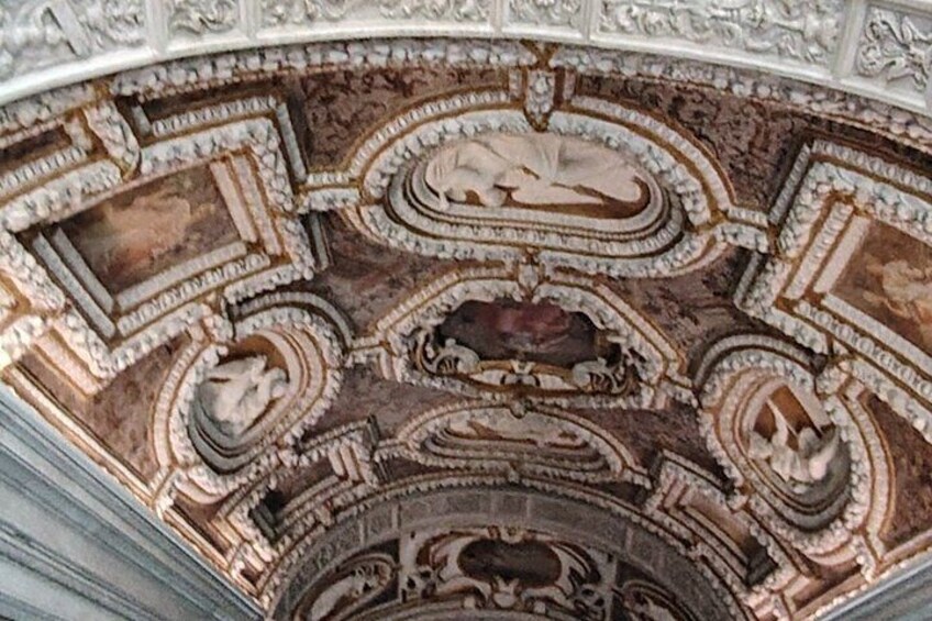 Un plafond richement décoré, orné de sculptures complexes et présentant un motif circulaire central. 4
