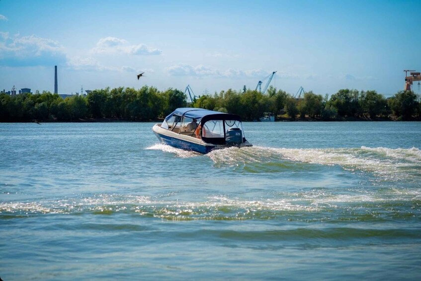 A speedboat on a river with industrial structures in the background. 2