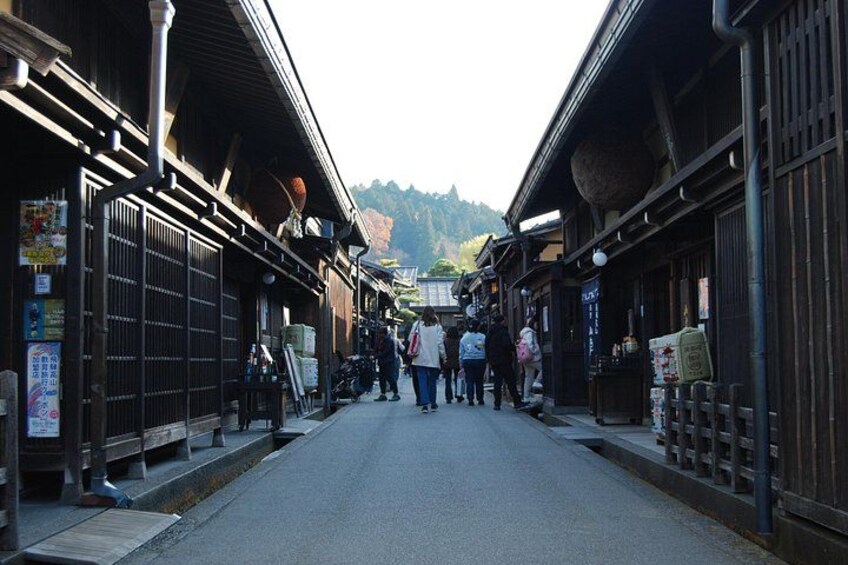 A traditional Japanese street with wooden buildings, a clear sky, and a few pedestrians. 3