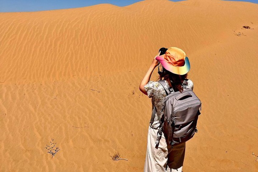 A person taking a photo of a sand dune. 4