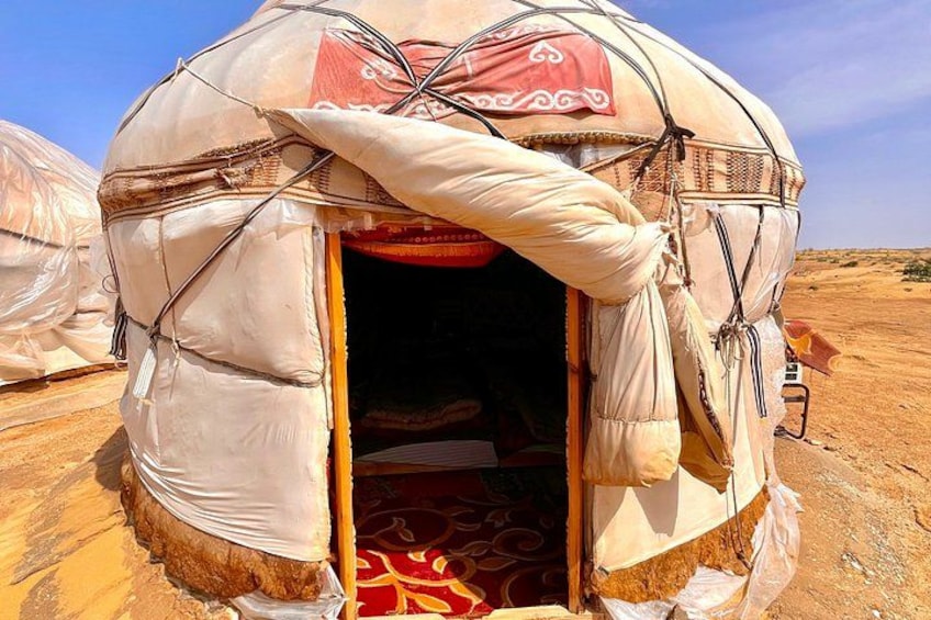 A traditional yurt with a red and white patterned fabric hanging over the entrance. 2