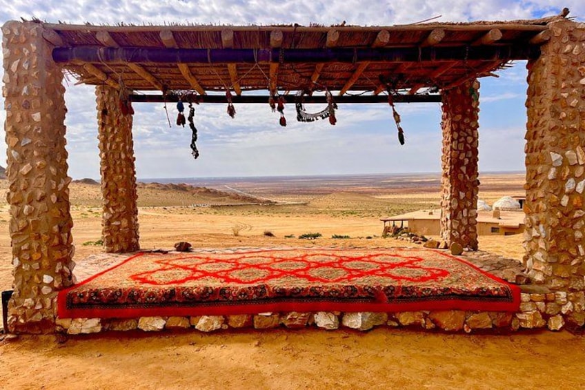 A stone structure with a red carpet, set against a desert landscape. 3