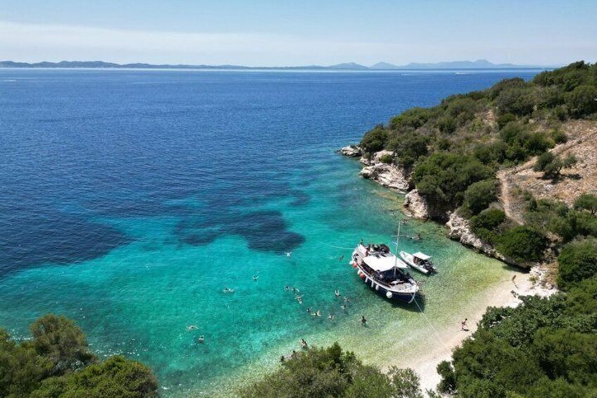 A coastal area with clear turquoise waters, boats anchored near the shore, and a hilly landscape with dense greenery. 3