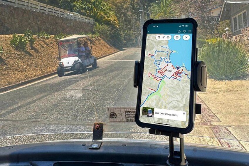 En smartphone monteret på et instrumentbræt, der viser et kort med en rute for en golfvogn. 3